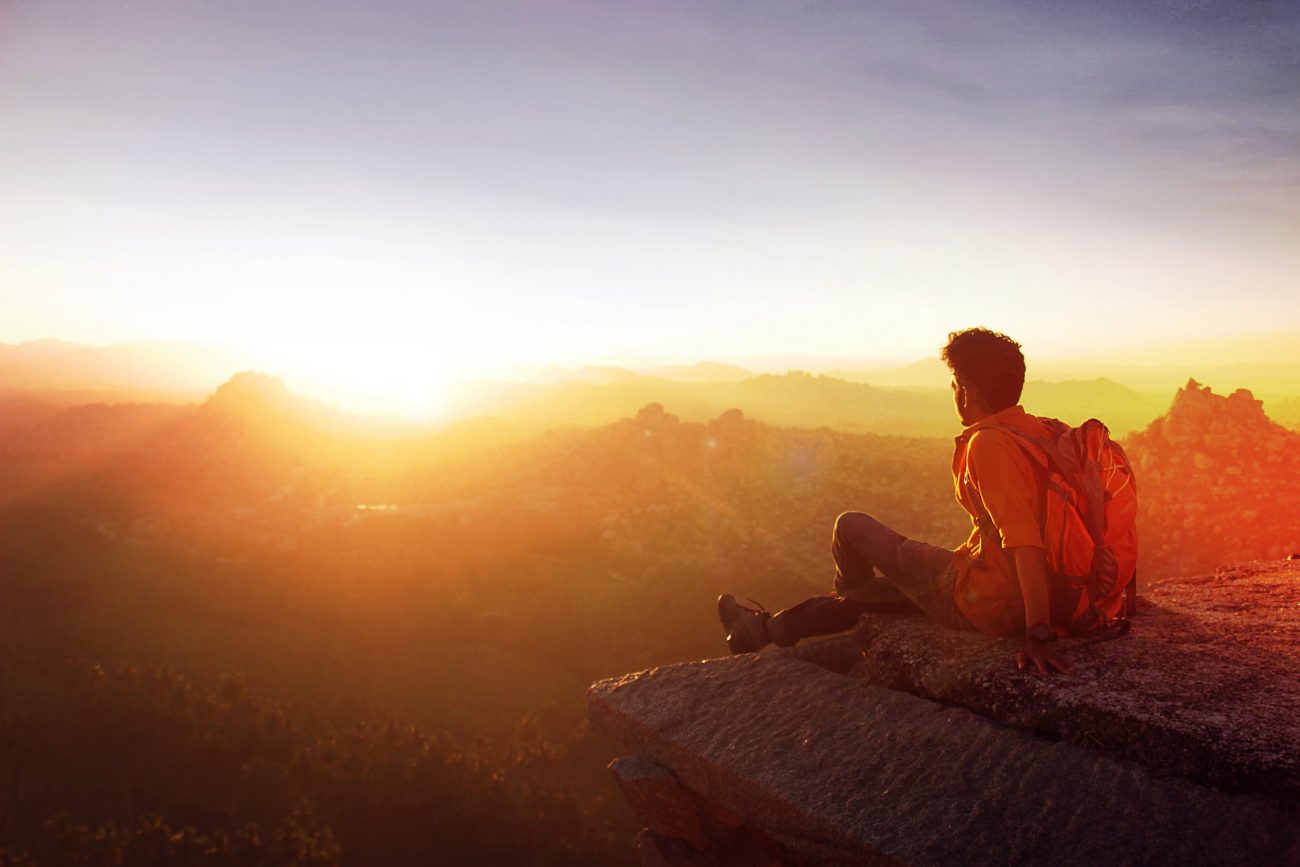 Man sitting on a mountain ridge at sunrise, men's counseling in Denver