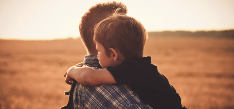 Dad hugging his young son in a golden field, therapy for fathers in Denver